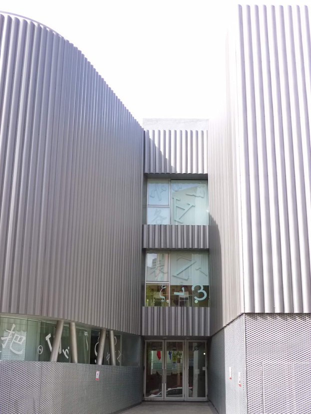 Ein modernes, großes Schulgebäude mit zahlreichen Fenstern und einer Tür, vor einem Himmel als Hintergrund.