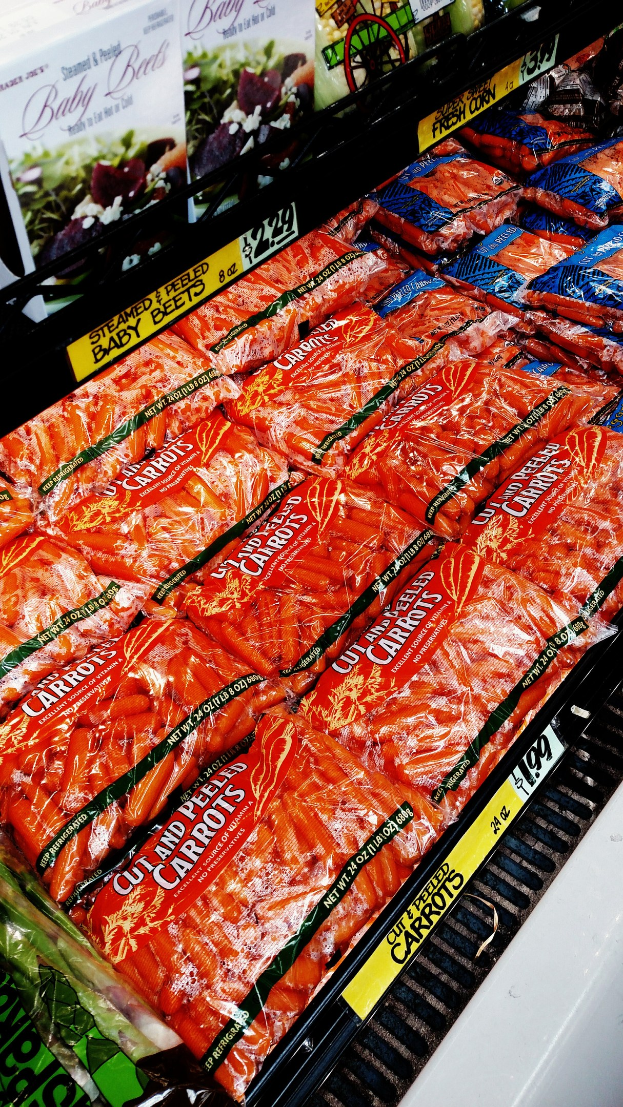 Ein Supermarktregal mit verschiedenen Lebensmitteln, darunter Gemüsepackungen, jeweils mit angebrachten Preisschildern.
