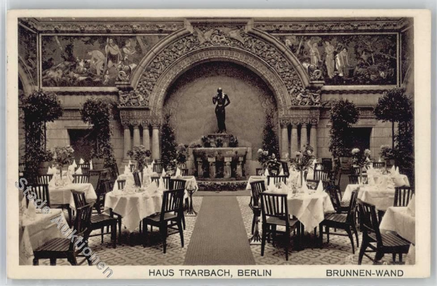 Ein altes Schwarz-Weiß-Foto eines Berliner Restaurants mit Tischen, Stühlen, Blumenvasen, einer Statue, Skulpturen und Pflanzen an den Wänden sowie Text am unteren Bildrand.