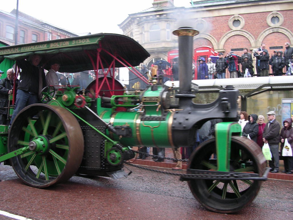 Ein Motor in der Mitte mit Gebäuden oben und Menschen auf der rechten Seite.