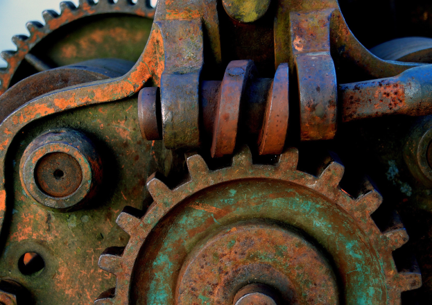 Nahaufnahme eines verrosteten Metallzahnrades mit mehreren Zähnen und Zahnrädern, das Zeichen von Abnutzung und Alter zeigt.