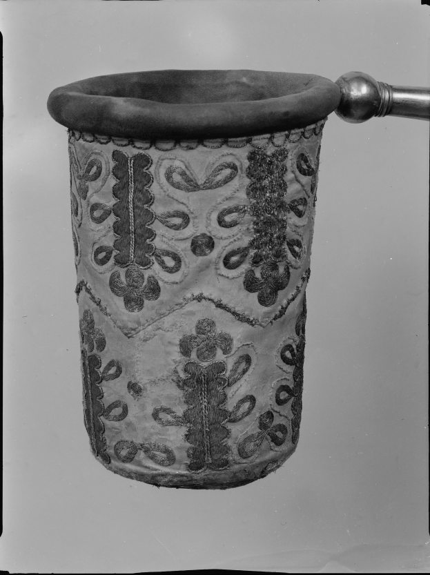 Ein Schwarz-Weiß-Foto eines Stoff-Müllpapierkorb mit Griff.