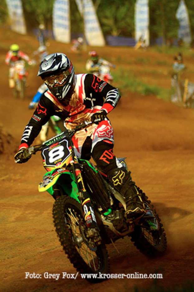 Mehrere Motorradfahrer bei einem Rennen, alle mit Helmen, mit Text unten im Bild.