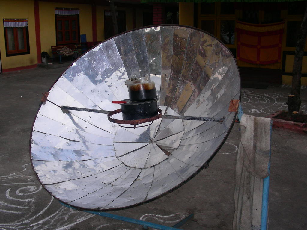 Eine Antenne ist auf einem Mast neben einer Straße montiert, mit einem Haus mit Türen und Fenstern im Hintergrund.
