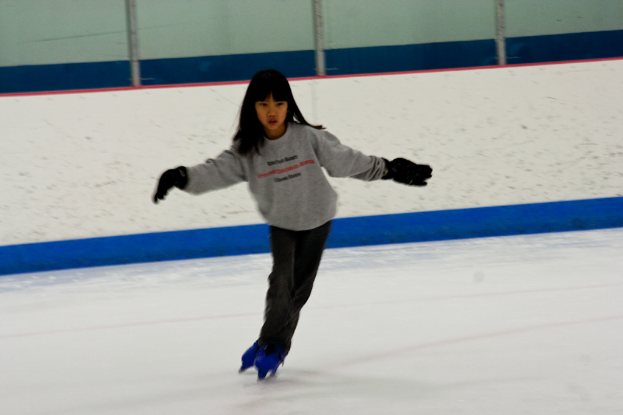Eine Person in Kleidung fährt auf dem Eis mit Polen an der Bildoberseite.