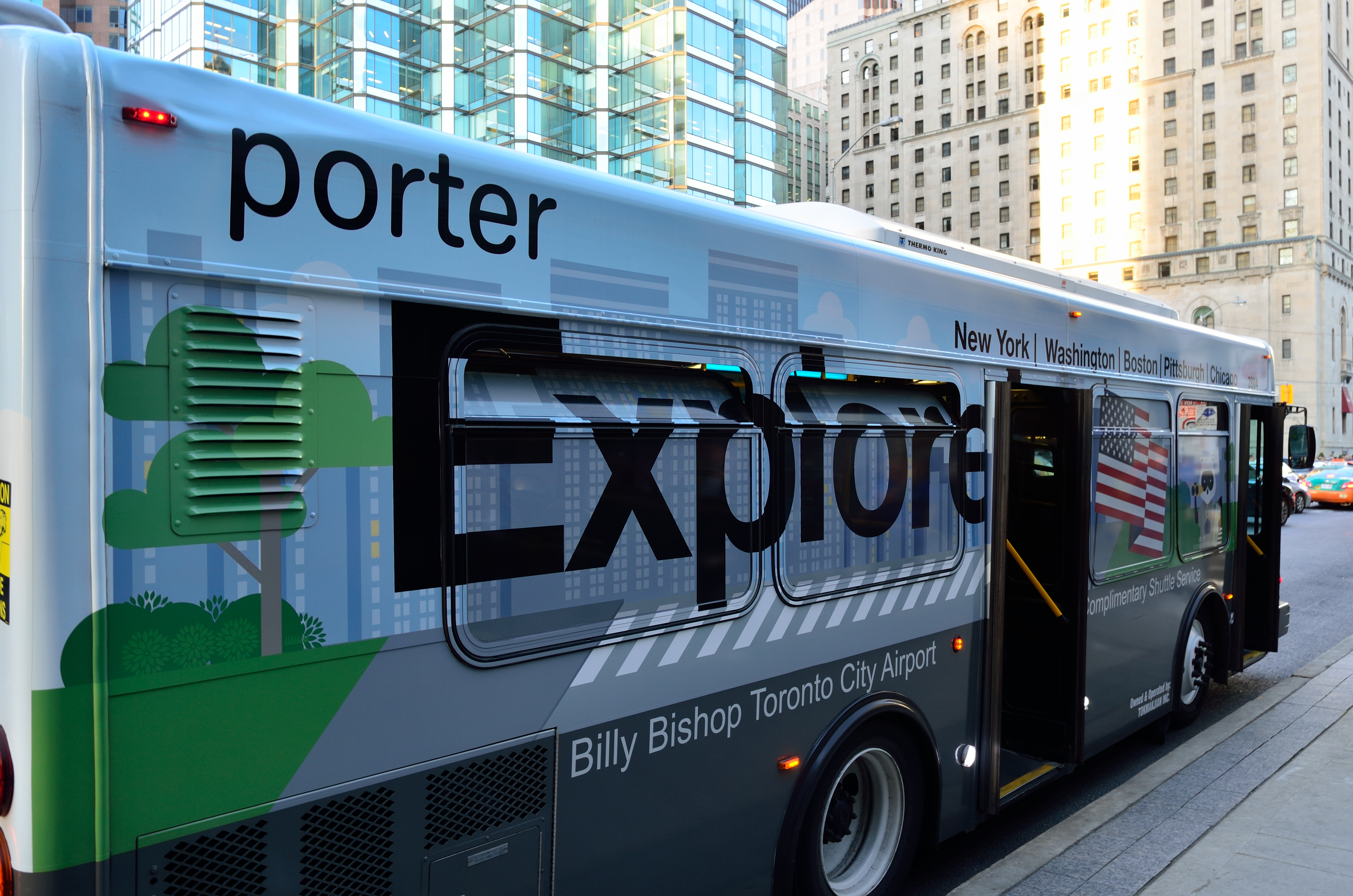 Ein Porter Express-Bus steht auf der Seite einer Stadtstraße, umgeben von hohen Gebäuden, mit einem Fußweg auf der rechten Seite.