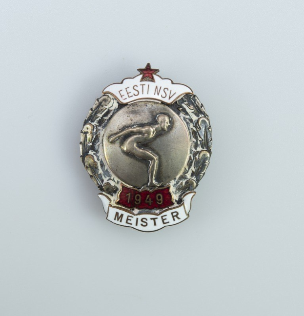Eine silberne Abzeichen mit einem roten Stern und Text, Emblem der Olympischen Spiele 1949 in Deutschland.