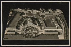 Schwarzes und weißes Rahmenfoto eines detaillierten Modellkonzerthauses mit einer großen zentralen Kuppel und steinernen Wänden, umgeben von einem Metalldach und einer Menge, mit einer hell erleuchteten Bühne.