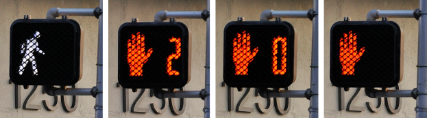 Eine Ampel an einem Gebäude befestigt, die drei verschiedene Arten von Verkehrssignalen anzeigt.