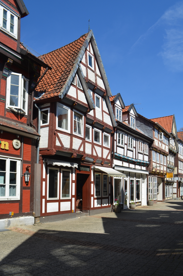 Eine Kopfsteinpflasterstraße im alten Stadtkern von Heidelberg mit Gebäuden im Vordergrund, einem klaren blauen Himmel im Hintergrund und einer Lampe, die die Straße auf der linken Seite beleuchtet.