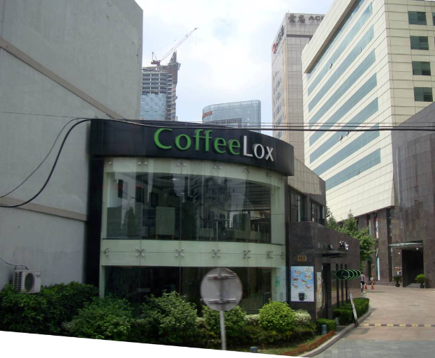 Ein Geschäftsgebäude mit einigen Pflanzen davor, Kabel und vielen Hochhäusern im Hintergrund.