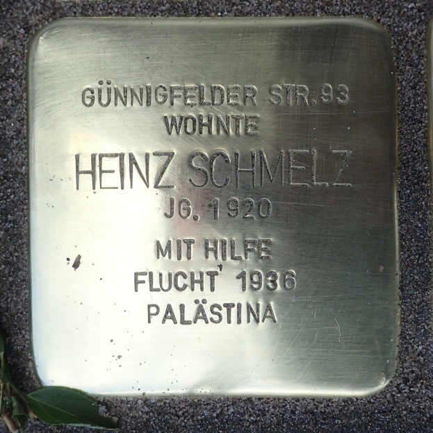 Messingplatte am Boden mit der Inschrift "Heinz Schmelz", umgeben von welken Blättern.