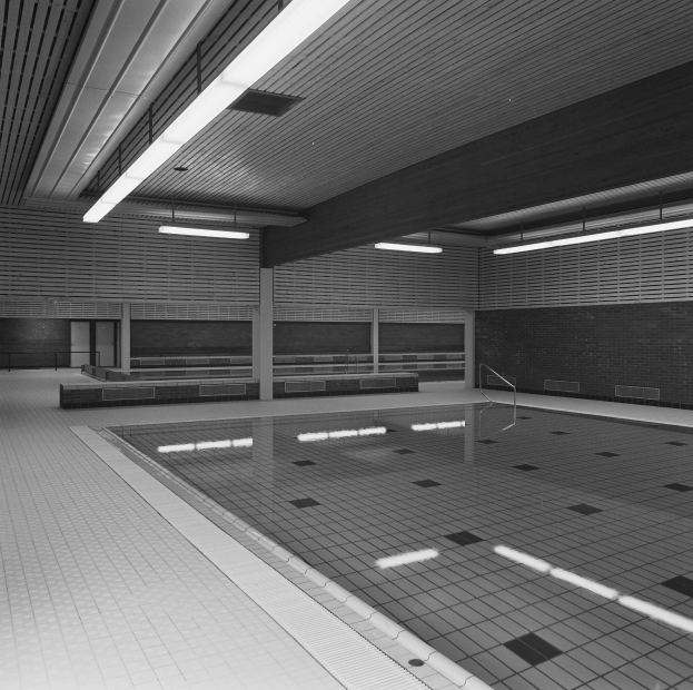 Indoor-Schwimmbad mit klarem Wasser, gefliesten Wänden und Boden, Deckenbeleuchtung und minimalen Umgebungsgegenständen in einer ruhigen Umgebung.