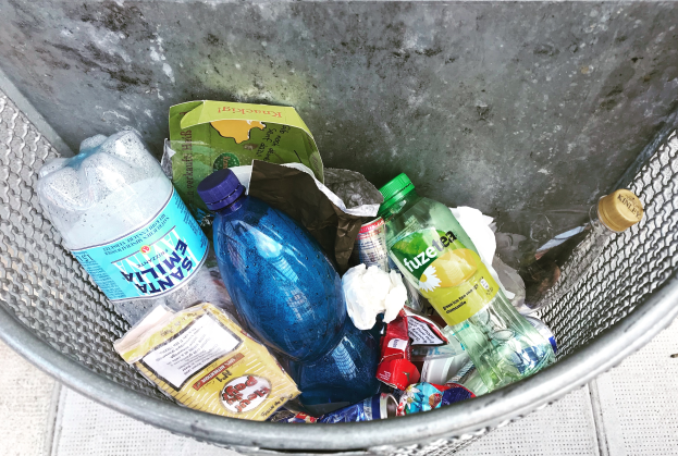 Ein Metallmüllcontainer gefüllt mit Plastikflaschen, Tüten und anderen Gegenständen.