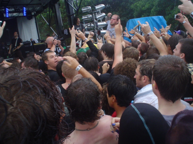 Eine Gruppe von Menschen, die unter einem Schutz stehen, mit Eisenstangen und einem blauen Plan im Hintergrund.