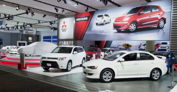 Eine Autohalle mit mehreren Fahrzeugen, einem Banner an der Wand und mehreren Scheinwerfern an der Decke.