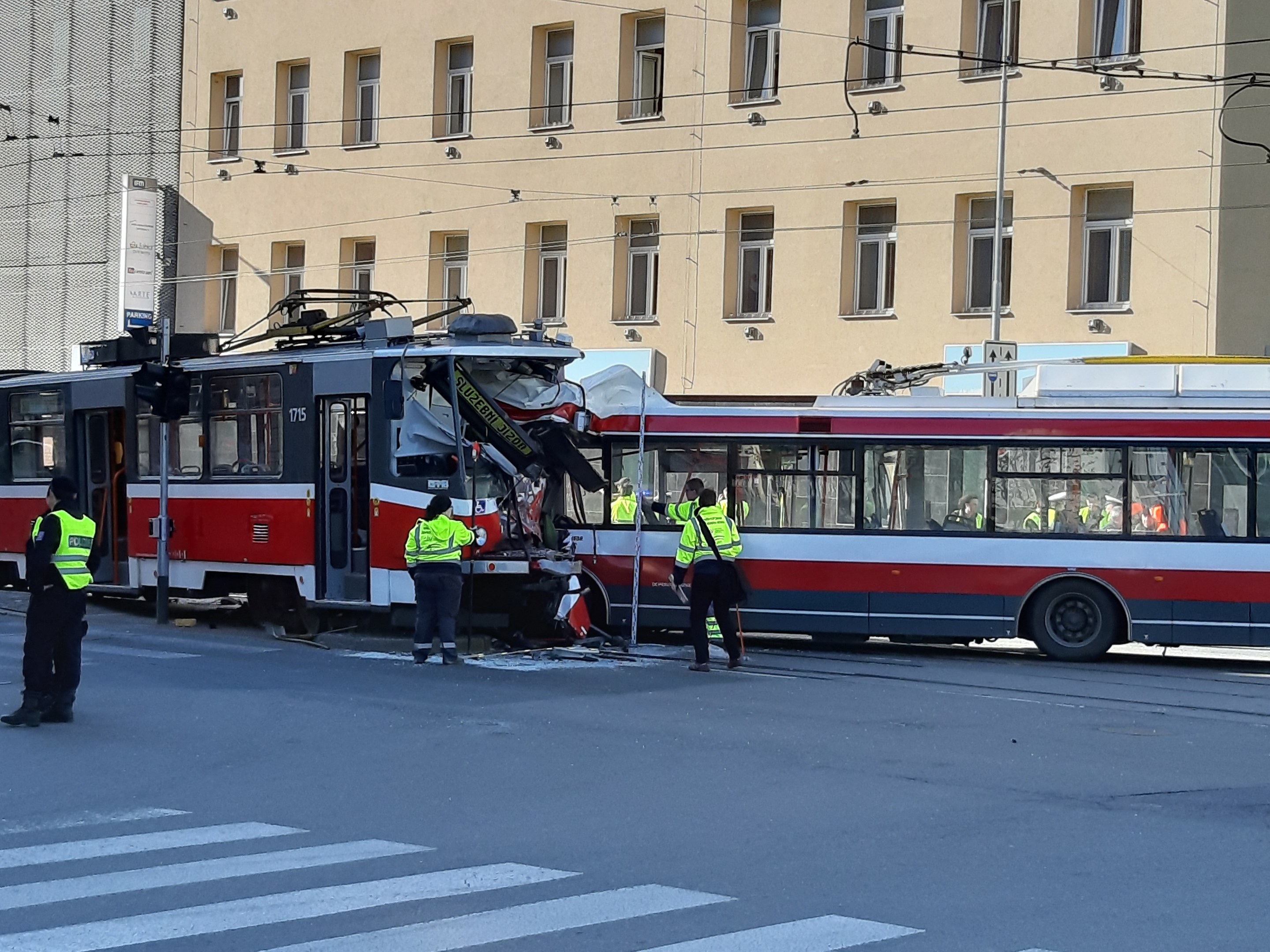 Rote und weiße Straßenbahn krachte auf der Straße mit einigen Menschen in der Nähe und einem Gebäude im Hintergrund.