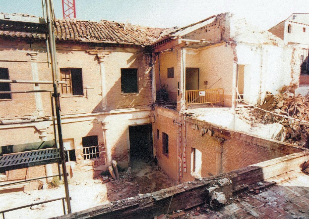 Ein teilweise abgerissener Bau mit einer Barriere, sichtbaren Fenstern und etwas, das wie eine Leiter aussieht.