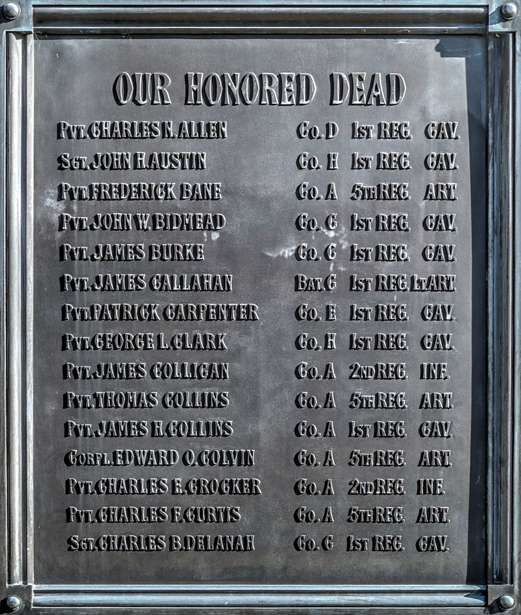 Gedenktafel an einer Gebäudeseite mit der Inschrift "Unser Ehrwürdiger Toten" aus Metall.