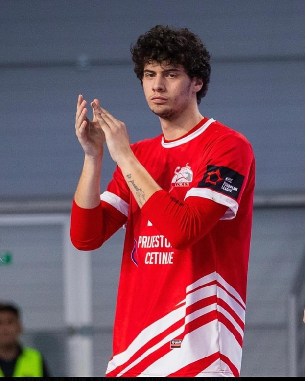 Ein Mann in einem roten und weißen Hemd klatscht im Vordergrund mit einer anderen Person und einer Wand im Hintergrund, mit dem Text "Copenhagen Futsal Club - Foto 1" unten.