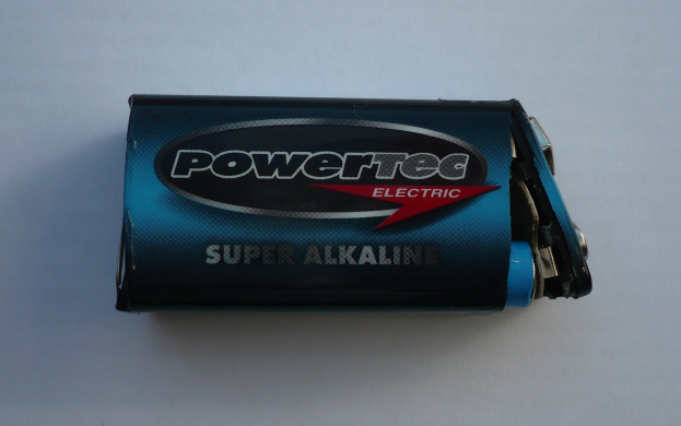 Blue Powertec Super Alkaline battery labeled "Powertec" on a white surface.