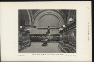 Schwarze und weiße Fotografie des Banketts der National Park Bank in New York City, mit Tischen, Lampen, einer Uhr an der Wand und Text unten.