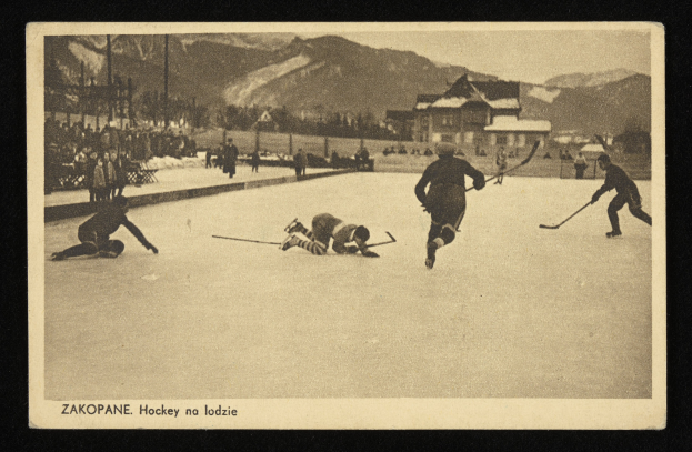 Schwarzes und weißes Foto von Menschen, die Hockey auf einem Eisplatz spielen, mit Gebäuden, Bäumen, Pfählen und Bergen im Hintergrund, einschließlich Text unten.