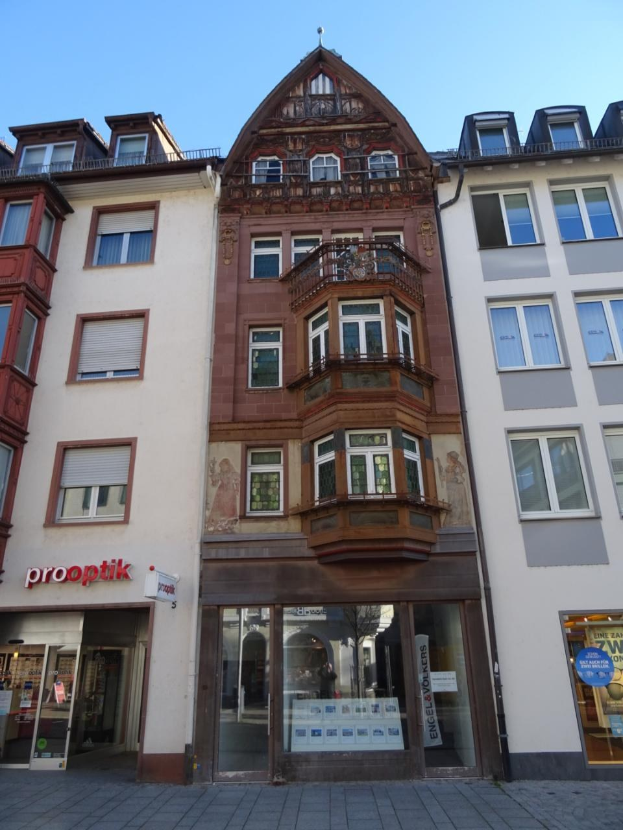 Gewerbliches Immobilienangebot in Heidelberg, Deutschland, mit einem mehrfenstrigen Gebäude an einer Straße mit einem klaren blauen Himmel.