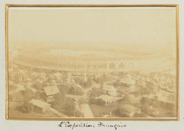 Altes Schwarz-Wei├č-Foto eines Stadions inmitten einer Stadt mit umgebenen Geb├Ąuden, B├Ąumen und Masten, mit Text unten.