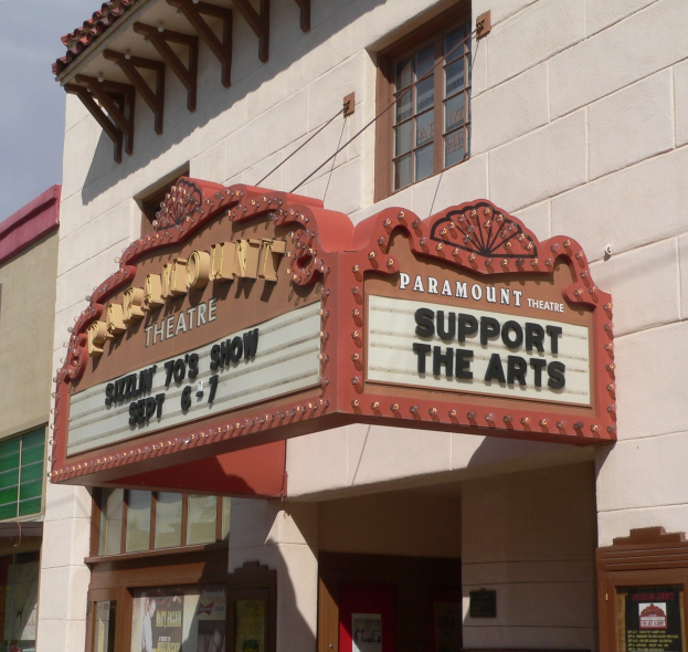 Außenansicht des Paramount Theatre in Sacramento, Kalifornien, mit Glasfenstern und -türen, einem 'Support the Arts'-Schild und dem Himmel im Hintergrund.