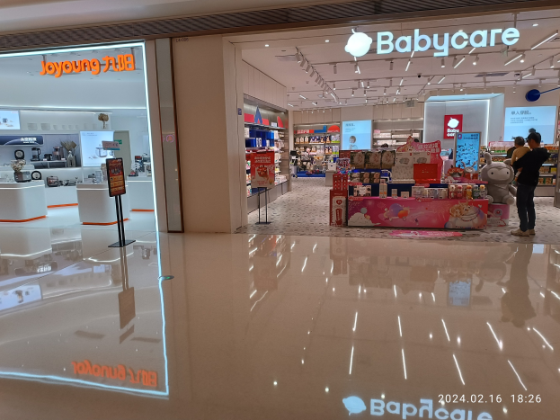 Ein Babypflegegeschäft in einem Einkaufszentrum mit Menschen, Spielzeugen, Regalen, Schildern, einem Anzeigebildschirm und Deckenleuchten, das sich im Mall of Asia befindet.