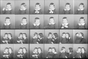 Schwarz-weiß-Foto einer Gruppe von Kindern mit einer Frau in der Mitte, die ein Baby hält und beide warm lächeln