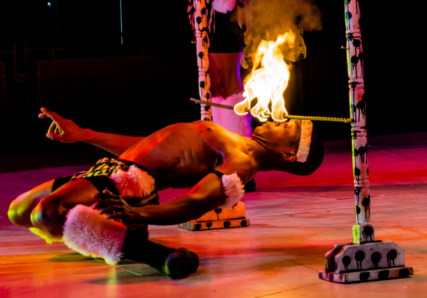 Eine Person schaut auf ein Feuer, das auf einer Stange an Pfählen hängt.