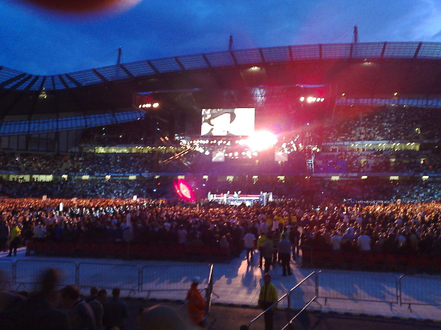 Eine Konzerthalle mit Menschen, Scheinwerfern und einer Projektionsfläche.