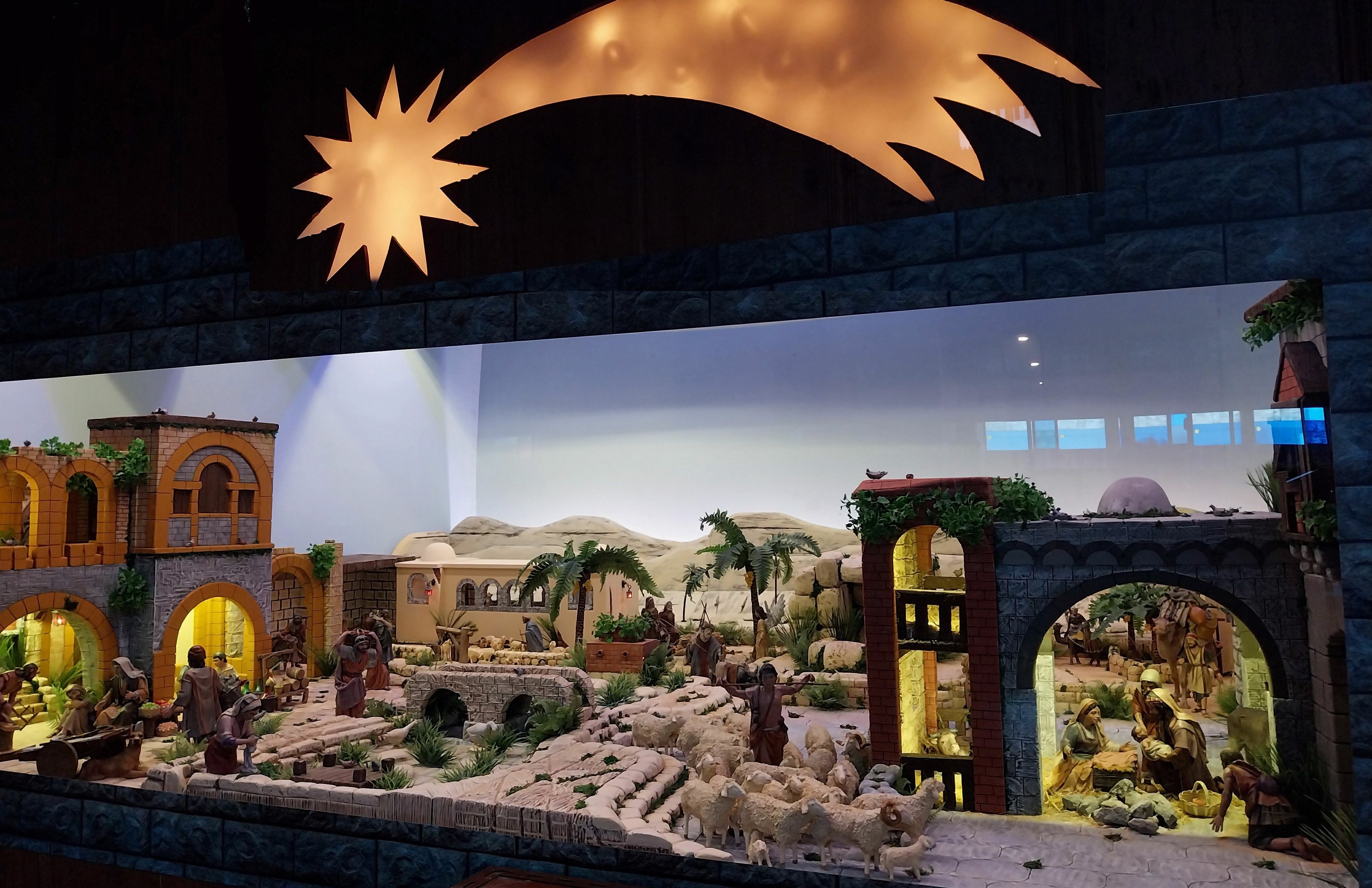 Eine Krippenausstellung im Museum mit Figuren, Tieren und Dekoration, beleuchtet von oben.