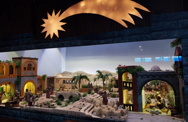 Eine Krippenausstellung im Museum mit Figuren, Tieren und Dekoration, beleuchtet von oben.